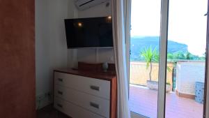 a room with a dresser with a tv and a window at La Costa del Pavone in Carini