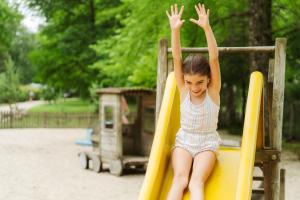 a young girl on a slide at a playground at Camping Etang de Sologne in Nouan-le-Fuzelier