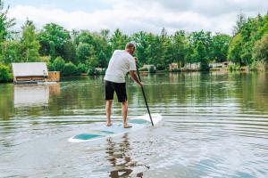 a man on a paddle board in the water at Camping Etang de Sologne in Nouan-le-Fuzelier