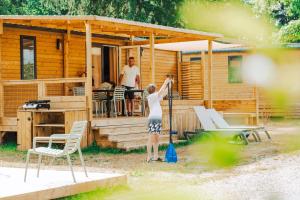 a woman is standing in front of a cabin at Camping Etang de Sologne in Nouan-le-Fuzelier