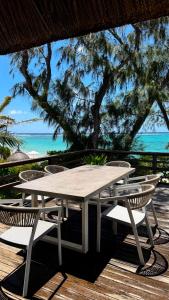 a white table and chairs on a deck with the ocean at BlueMoon Villa - Authentic, seaside living in Trou d'Eau Douce