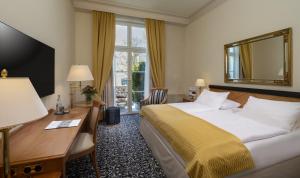 a hotel room with a bed and a desk and a mirror at Potsdam Hotel Am Jägertor in Potsdam