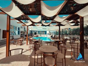 a patio with tables and chairs and a swimming pool at نادي البحارة الدولي - International Seamans Club in Suez