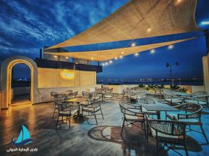 a rooftop patio with tables and chairs at night at نادي البحارة الدولي - International Seamans Club in Suez