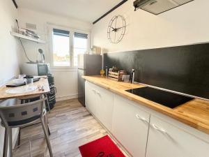 a kitchen with a counter and a table and a refrigerator at Chez Mamie Cloclo in Calais