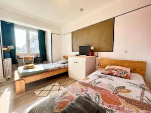 a bedroom with two beds and a flat screen tv at Chez Mamie Cloclo in Calais