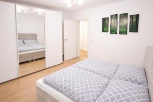 a white bedroom with a bed and a mirror at Ferienwohnung Westerwaldblick großzügige Wohlfühloase mit Terrasse in Oberelbert