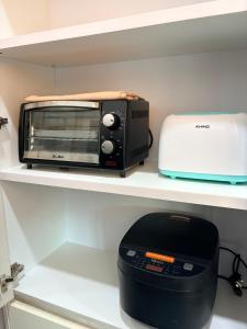 a toaster and toaster oven sitting on a shelf at Homestay Aydan at Kijal Kemaman in Cukai