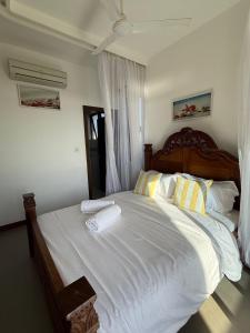 a bedroom with a large bed with white sheets and yellow pillows at Sultan Palace Beach Resort - AMANI Apartment CB2-202 in Kikambala +13 photos