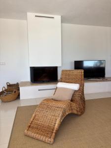 a living room with a wicker chair and a television at Villa Casiopea in Illes Balears