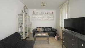 a living room with a black couch and a tv at Garda Prestige Retreat in Moniga