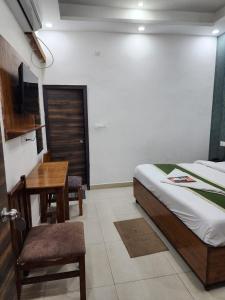 a bedroom with a bed and a table and a desk at Frolic Hotel Near Sec 52 Noida Metro Station in Noida