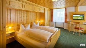 a bedroom with a bed and a desk and a television at Landhotel Löwen Bernau in Bernau im Schwarzwald