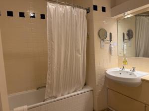 a bathroom with a sink and a shower curtain at Red Lion Hotel by Greene King Inns in Fareham +42 photos