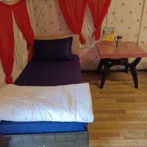 a bed in a room with a table and curtains at Down Valley Resort in Rishīkesh