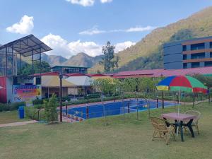 a table and chairs with an umbrella next to a pool at Down Valley Resort in Rishīkesh