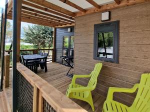 a porch with two green chairs and a table at Camping La Provençale - Maeva in Mandelieu-La Napoule