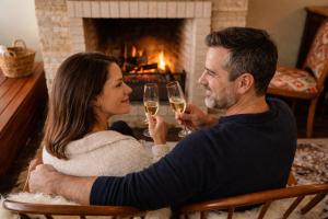 a man and woman drinking wine in front of a fireplace at Le Boutique Hotel Gramado - Exclusivo para Casais in Gramado