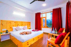a bedroom with a large bed with red curtains at Pinnacle view in Manāli