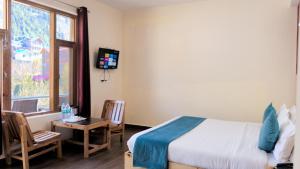 a bedroom with a bed and a table and a window at Pinnacle view in Manāli