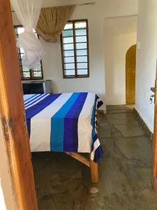 a bedroom with a bed with a blue and white comforter at Petcat Cottage in Diani Beach