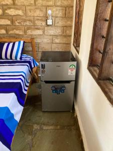 a small refrigerator in a room next to a bed at Petcat Cottage in Diani Beach