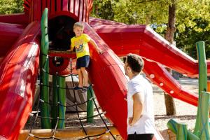 two young boys playing on a slide at a playground at Glavotok Premium Green Camp in Krk