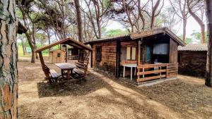 a log cabin with a table and a bench in front at Camping Bella Sardinia in S'archittu Cuglieri