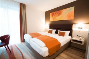 a hotel room with a large bed and a chair at Hotel Kapuzinerhof in Biberach an der Riß