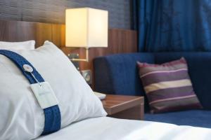 a hotel room with a bed with a pillow and a couch at Holiday Inn Express Lille Centre by IHG in Lille
