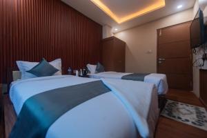 Hotel Nariyah في Dhungrebās: غرفة فندق بها سريران وخزانة ملابس