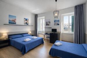 a bedroom with two beds and a desk and two windows at Hotel Britannia in Genoa