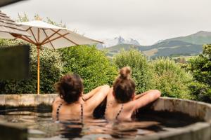 two women sitting in a swimming pool with an umbrella at L'Alpaga, a Beaumier hotel in Megève