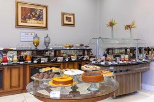 a bakery with cakes and pastries on a table at Hotel Flat Petras Residence in Curitiba