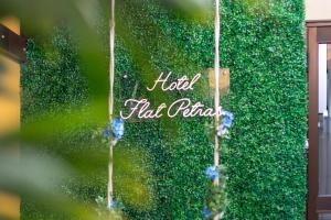 a green hedge with the words hello half pizza on it at Hotel Flat Petras Residence in Curitiba