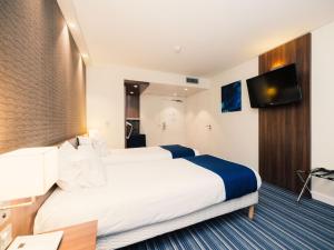 a hotel room with two beds and a flat screen tv at Holiday Inn Express Lille Centre by IHG in Lille
