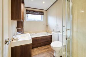 a bathroom with a toilet and a tub and a sink at Sutton Lodge with Hot Tub in York +21 photos
