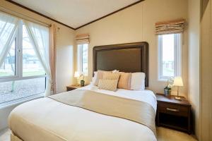 a bedroom with a large bed with two windows at Sutton Lodge with Hot Tub in York
