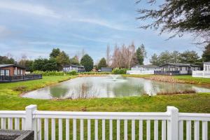a pond in a yard with a white fence at Sutton Lodge with Hot Tub in York