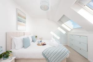 a white bedroom with a bed and a skylight at Little Chy an Mor in Coverack