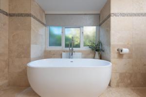 a large white tub in a bathroom with a window at Little Chy an Mor in Coverack +35 photos