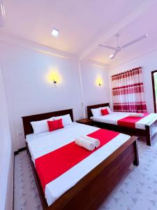 a bedroom with two beds with red and white sheets at Shan Villa Dambulla in Dambulla