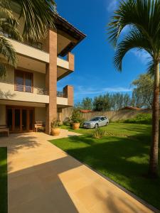 a car parked in front of a building with a palm tree at Espaço Verão Vermelho in Cabo Frio