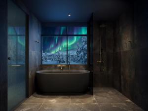 a bathroom with a tub and a window with the northern lights at Arcora Boutique Hotel & Villas in Muonio
