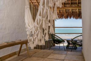 a room with a hammock and chairs and the ocean at Villa Água de Côco Preá in Prea