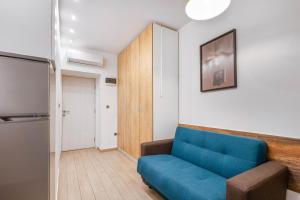 a living room with a blue couch and a refrigerator at Apartments Pomerio Rijeka East in Rijeka