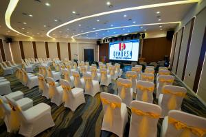 a conference room with white chairs and a screen at Dembesh Hotel Juba in Juba