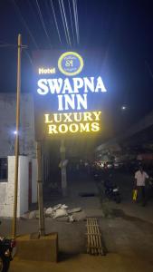 a sign for a hotel waveriaiminy rooms at night at Swapnainn in Ongole
