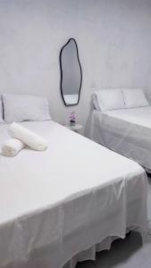 two beds in a room with a mirror on the wall at Águas de Maragogi residence in Maragogi