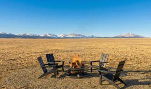 three chairs and a fire pit in the middle of a desert at Luxury Off-Grid Cabin with Stargazing Deck & Views in Fairplay